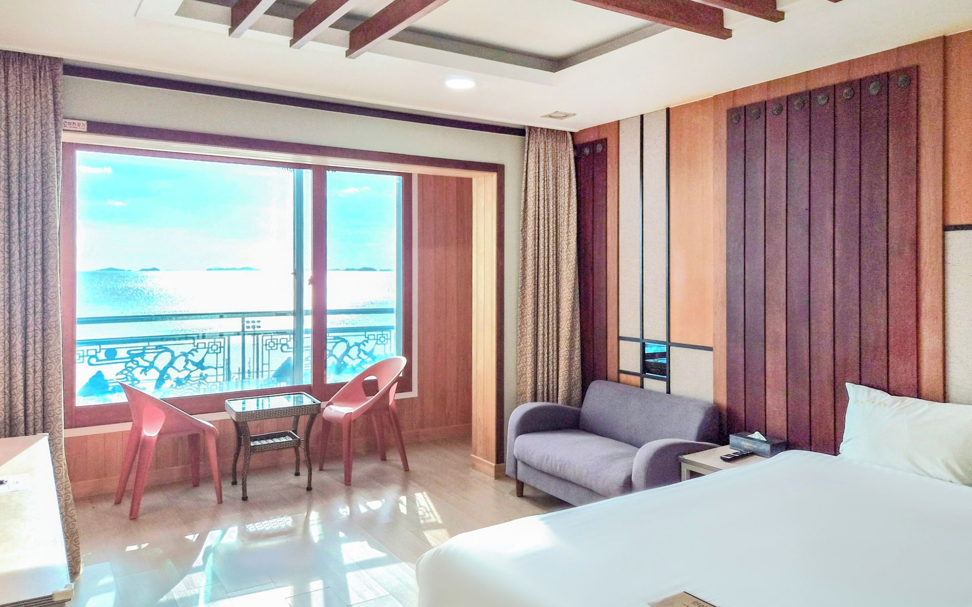 Quarto de hotel com varanda, cama, sofá, mesa e cadeira.