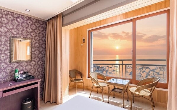 Une chambre d’hôtel avec un balcon, un bureau et une chaise.