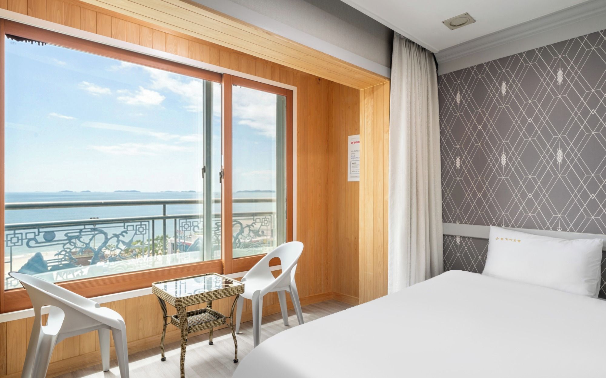 Een hotelkamer met een groot bed, een balkon met uitzicht op zee en een kamer met een patroon op de muur.
