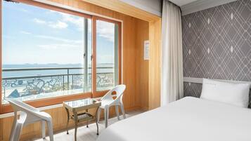 Een hotelkamer met een groot bed, een balkon met uitzicht op zee en een kamer met een patroon op de muur.