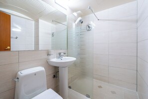 Uma casa de banho moderna com sanita, lavatório e cabine de duche em vidro.