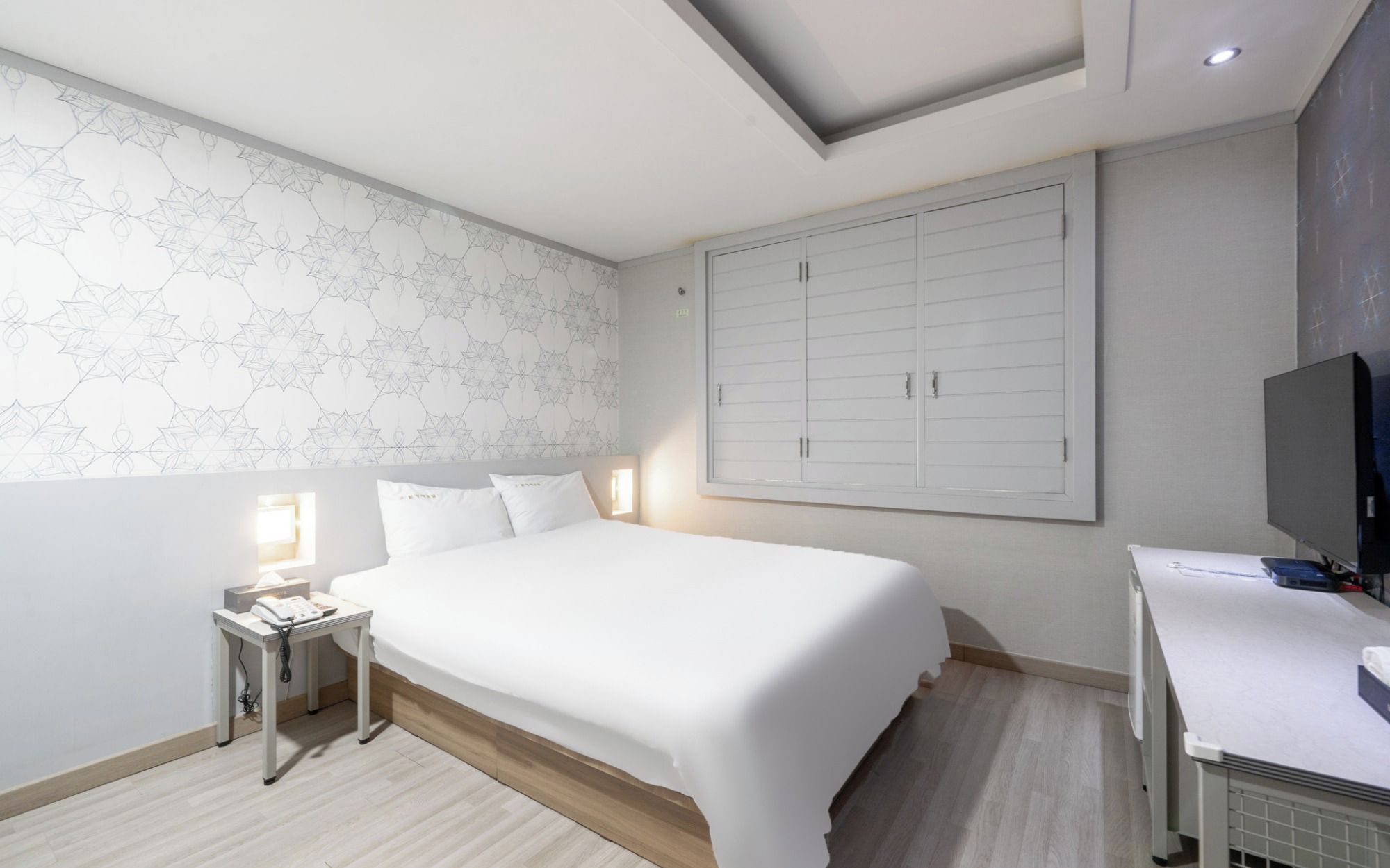 Quarto moderno com cama grande, mesa de cabeceira e guarda-roupa.
