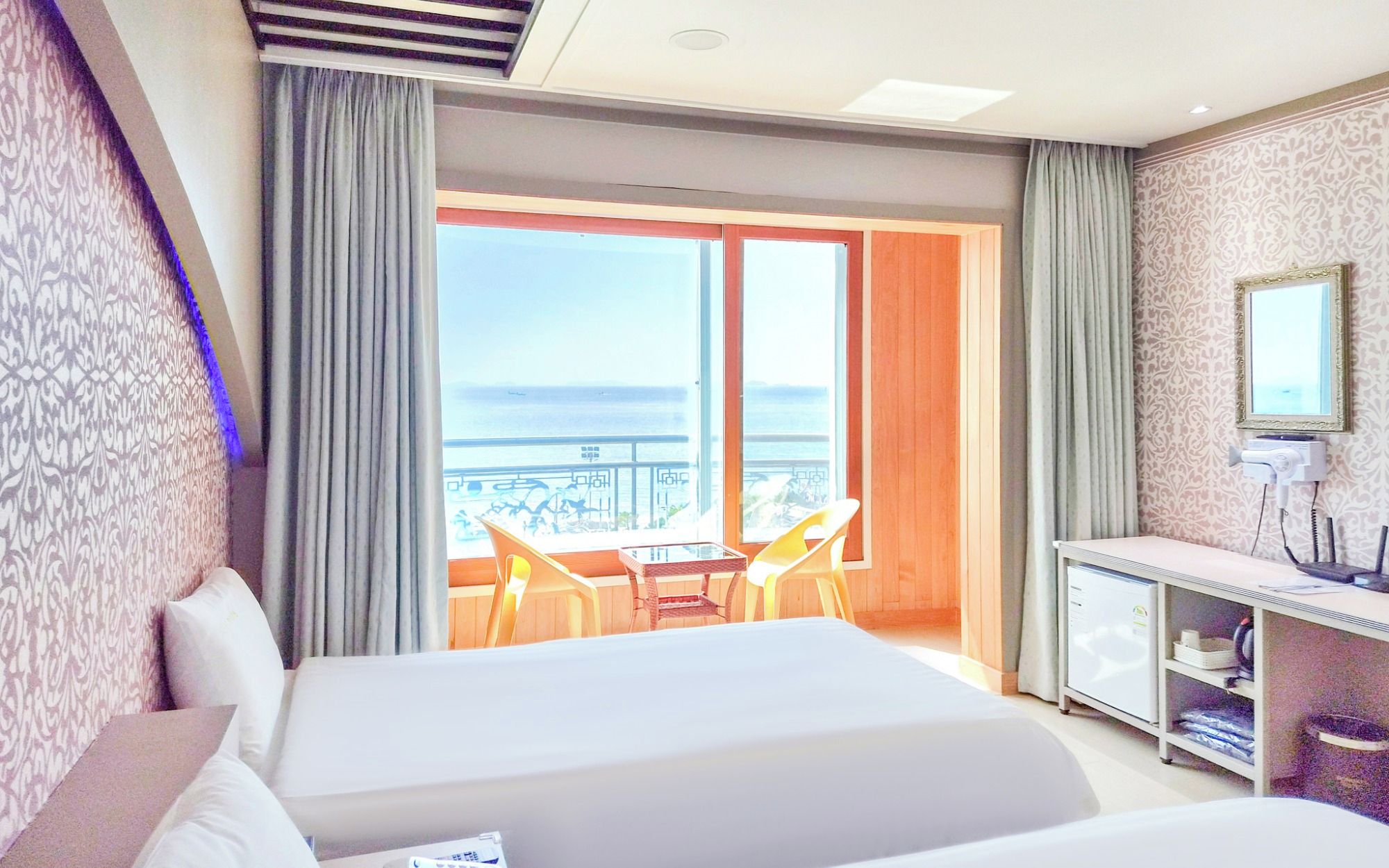 Una habitación de hotel con cama, escritorio, silla y vista al mar.