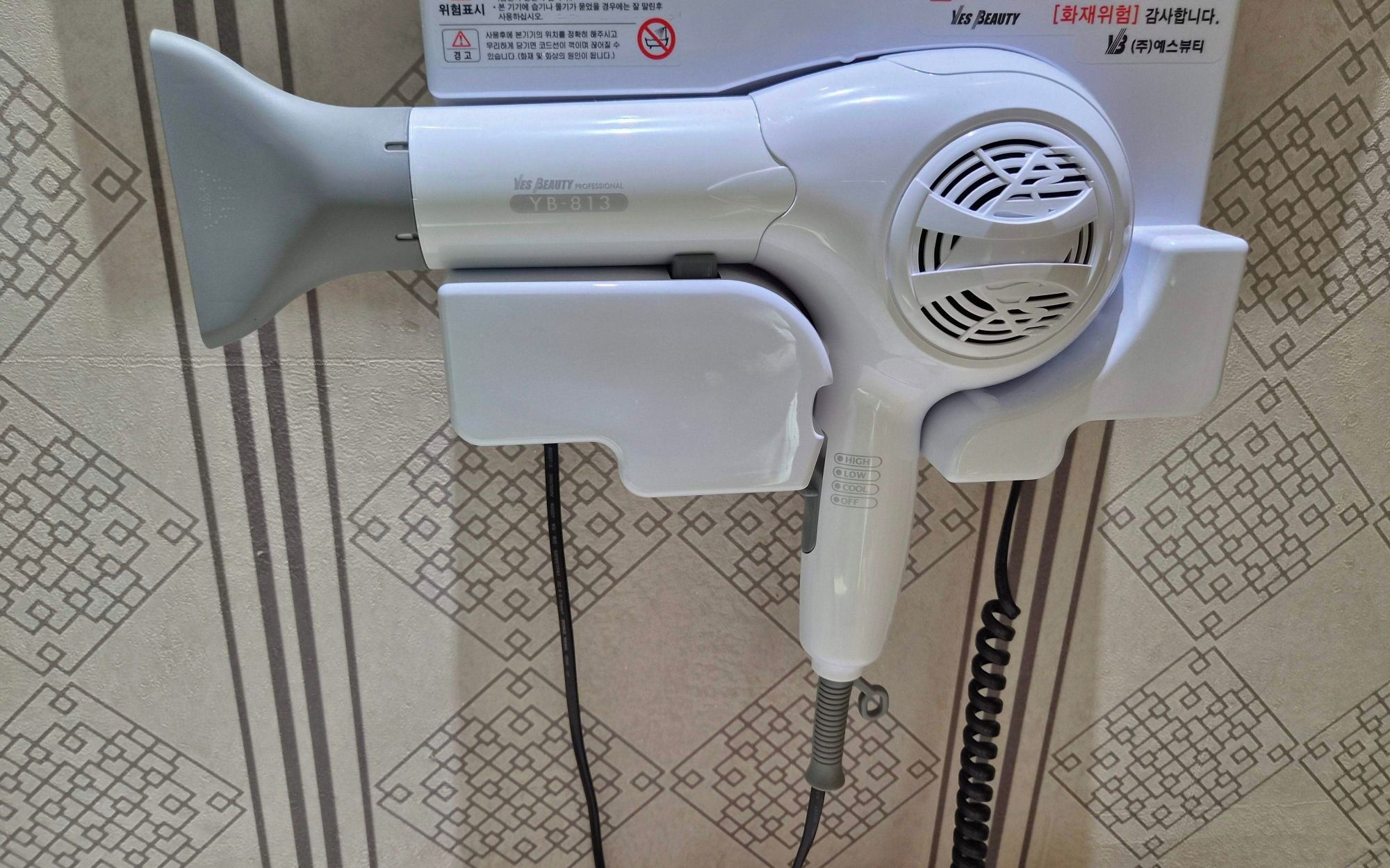 Un secador de pelo montado en la pared, con un diseño de azulejos estampados.