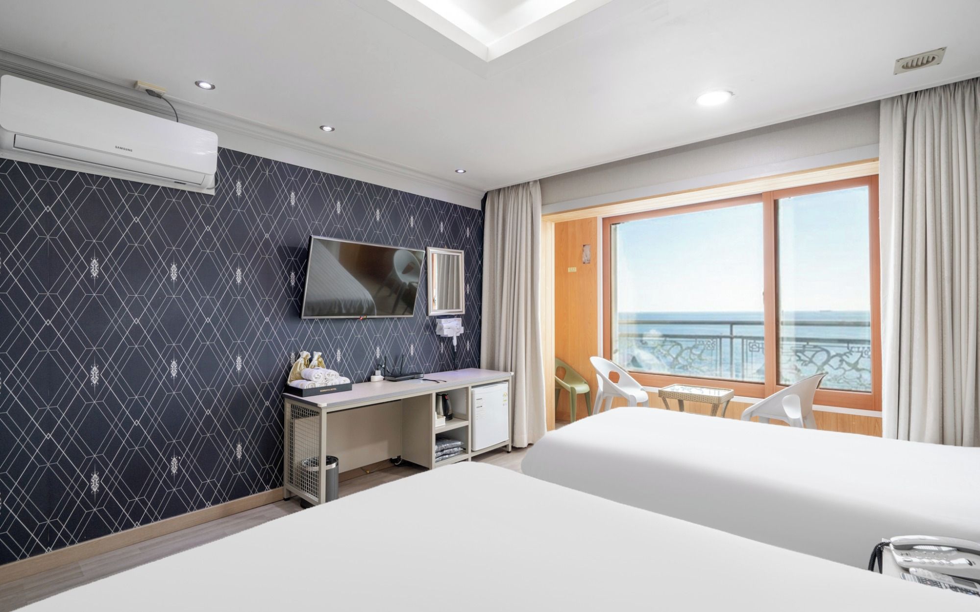 Habitación de hotel con cama, escritorio, televisor, balcón con vistas y ventana.