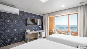 Habitación de hotel con cama, escritorio, televisor, balcón con vistas y ventana.