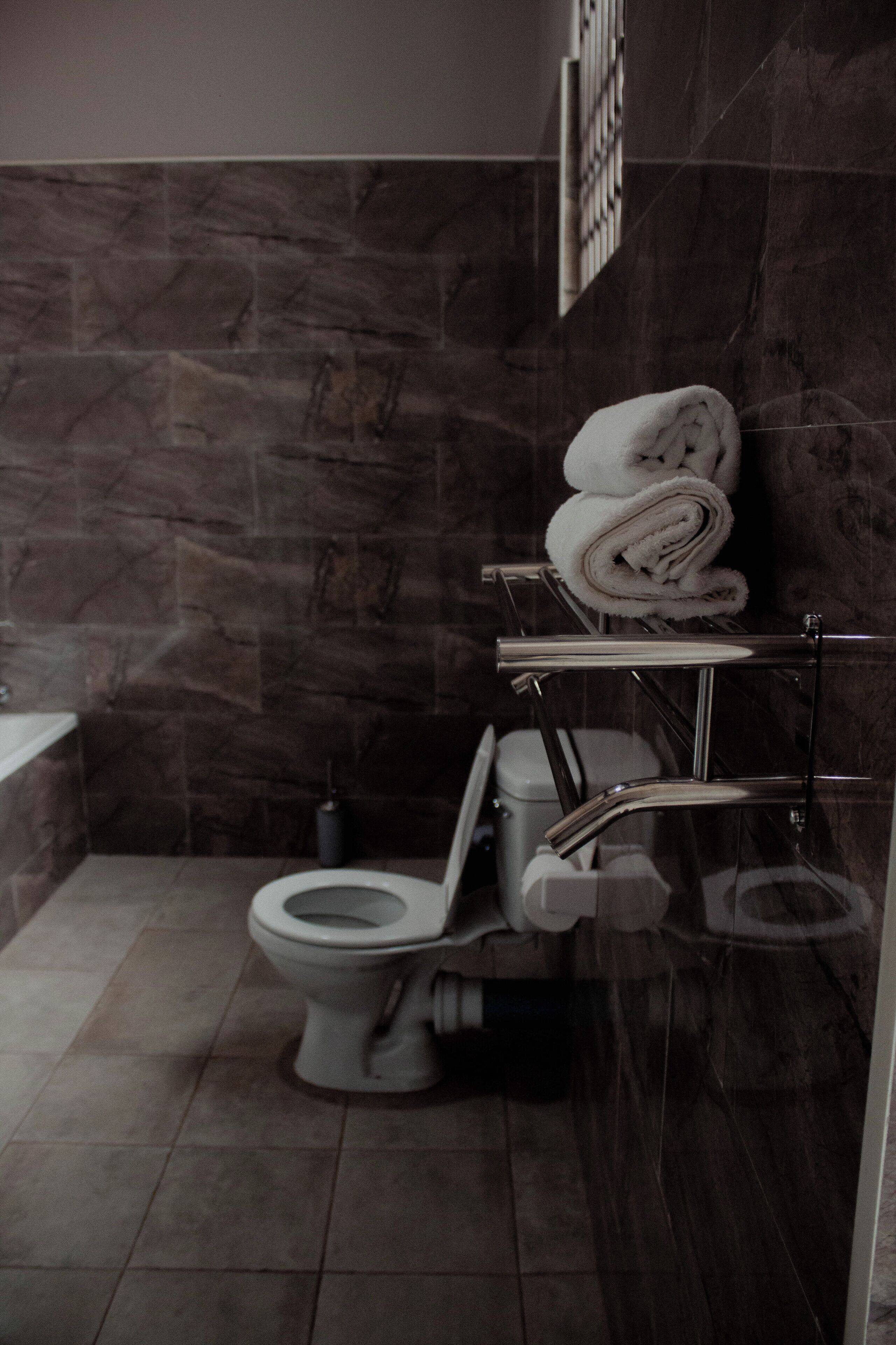 A modern bathroom with a toilet, a towel rack, and a shower area.