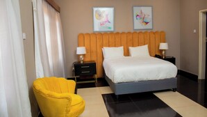 Ein Hotelzimmer mit einem Bett, zwei Nachttischen, einem gelben Sessel und zwei Wandbildern.
