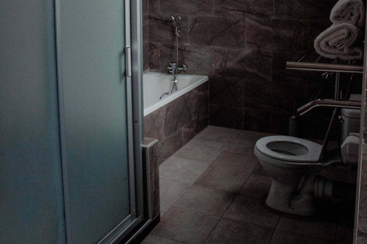 A bathroom with a glass shower enclosure, a bathtub, and a toilet.