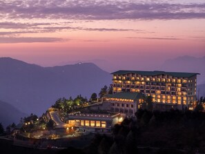 A multi-story hotel with a flat roof, located on a hillside with a view of mountains. - dusitD2, Fagu, Shimla (Theog)