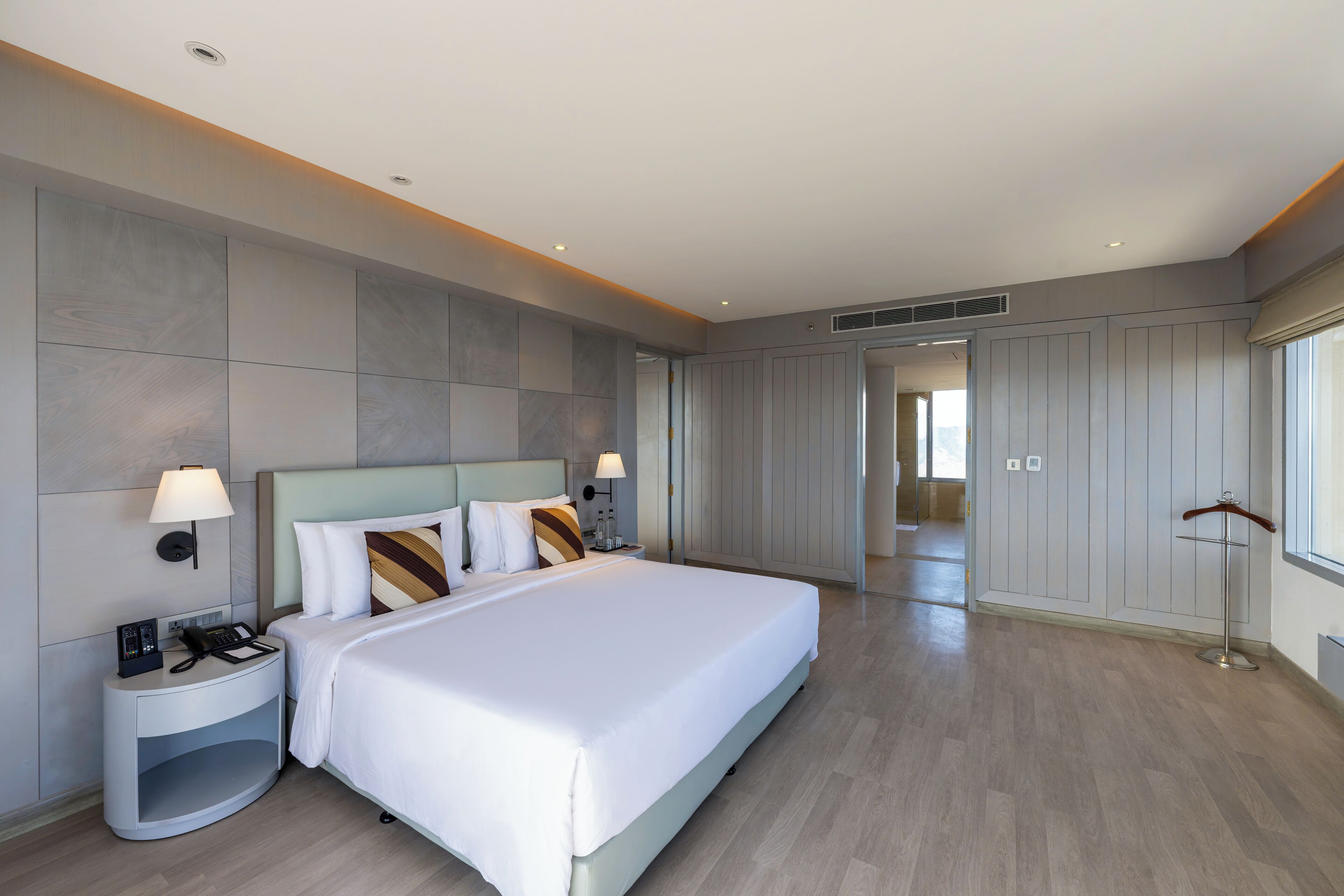 Una habitación de hotel moderna con una cama grande, lámparas de noche, una mesita de noche y un armario.