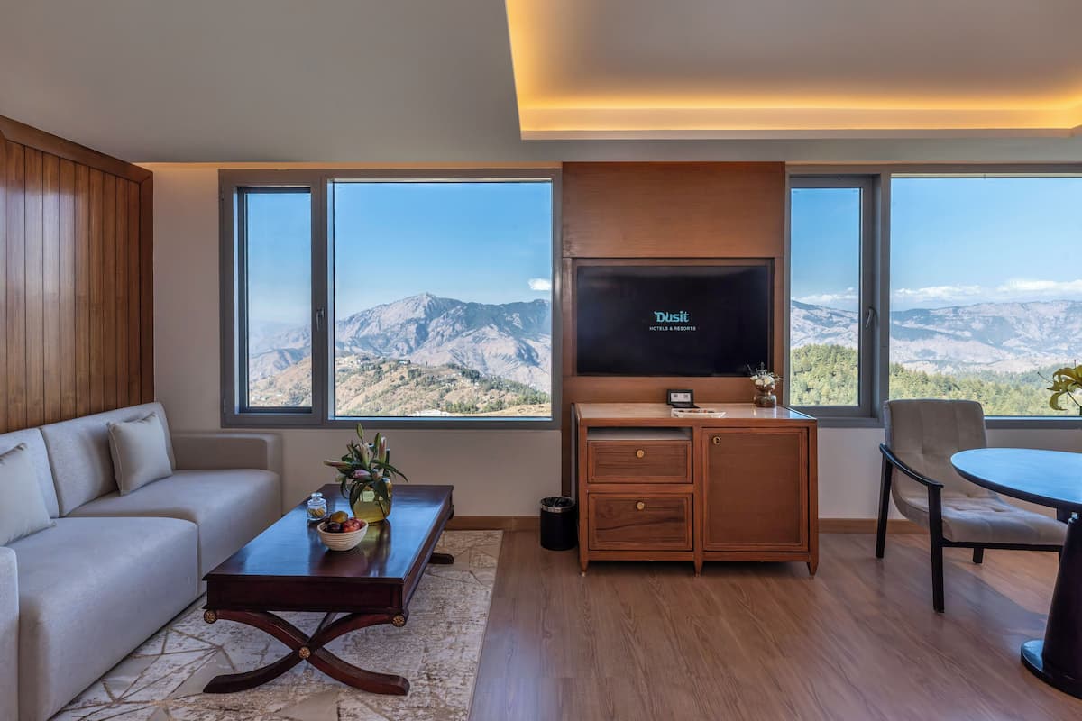 A modern living room with a large TV, wooden furniture, and a view of mountains.