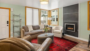 A living room with a sofa, armchair, ottoman, and a fireplace. - Tamarack Townhome #17 (Snowmass Village)