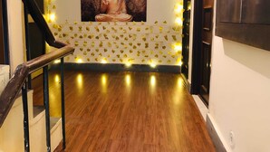 A staircase with a wooden handrail and a wall decorated with yellow leaf patterns and a Buddha statue. - EASY INN Holiday Home | 3BHK Apartment (Lucknow)