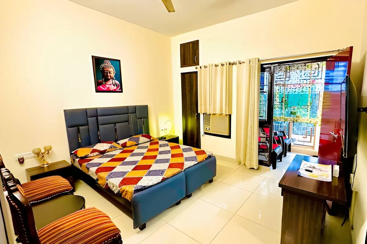 A hotel room with a bed, a desk, a chair, a TV, and a window with curtains.