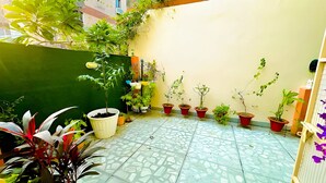 A small, enclosed garden area with various potted plants and a tiled floor. - EASY INN Holiday Home | 3BHK Apartment (Lucknow)