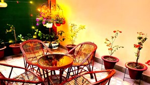 A patio with wicker chairs, a round table, and potted plants. - EASY INN Holiday Home | 3BHK Apartment (Lucknow)