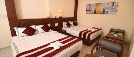 A hotel room with two beds, a ceiling fan, a painting, and a small table with a plant.