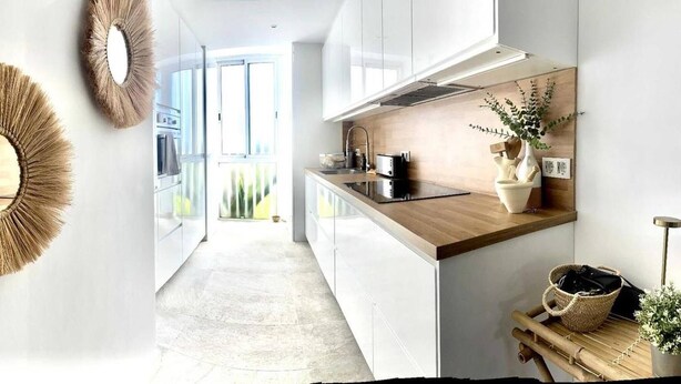 Una cocina moderna con armarios blancos, una encimera de madera y vistas al exterior.