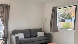 A modern living room with a grey sofa, a wooden coffee table, and a large woven rug. - Socialisers Dream on Arawa!  (Ohakune)
