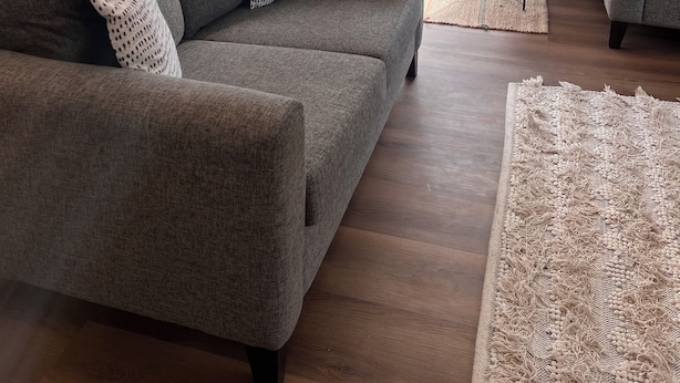 A modern living room with a grey sofa, two patterned pillows, a small round table, and a large window with curtains. - Socialisers Dream on Arawa!  (Ohakune)