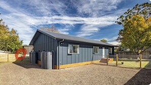 A single-story building with a sloped roof, large windows, and a gravel driveway. - Socialisers Dream on Arawa!  (Ohakune)