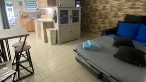 A compact living space with a kitchenette, a dining area, and a sofa with cushions. - One-bedroom apartment near Disney and Paris (Dampmart)