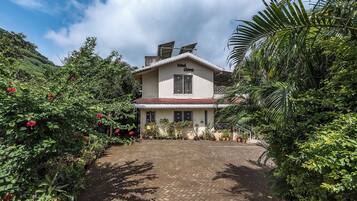Una casa de dos pisos con techo de tejas y un jardín delantero.