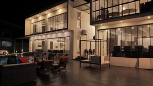 A modern outdoor seating area with a pool, chairs, and tables. - Magnolia - 3BR Private Pool Villa (Kanakapura)