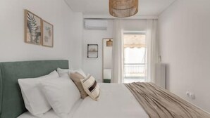 A bedroom with a bed, a hanging light fixture, and a window with curtains. - Prime 3BR Apartment in Ampelokipoi (Athina)