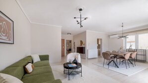 En moderne stue med en grøn sofa, et sofabord og et spiseområde med et bord og stole.
