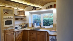 A kitchen with a large window, wooden cabinets, a built-in oven, and a tiled floor. - Romantic house with sauna and fireplace near the lake (Zossen)
