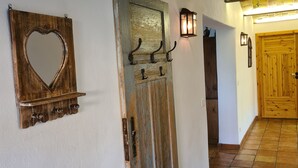 A hallway with a rustic wooden door, a heart-shaped mirror, and a wall-mounted light fixture. - Romantic house with sauna and fireplace near the lake (Zossen)
