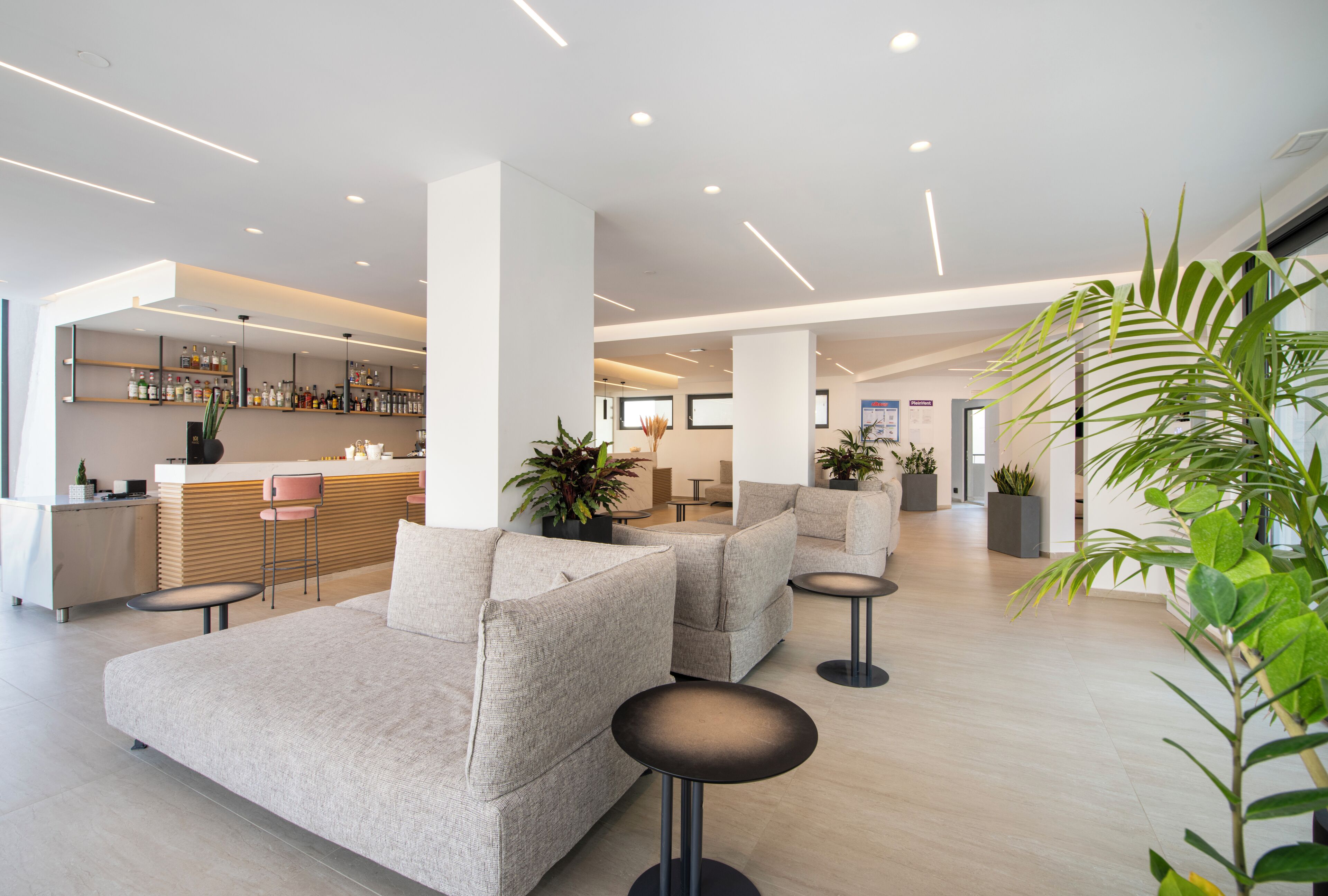 Eine moderne Lobby mit Sofas, einer Bar und Topfpflanzen.