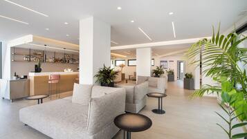 A modern lobby with sofas, a bar area, and potted plants.