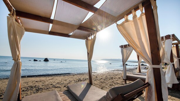 Eine Strandhütte mit Blick auf das Meer, Holzmöbel und ein klarer Himmel.