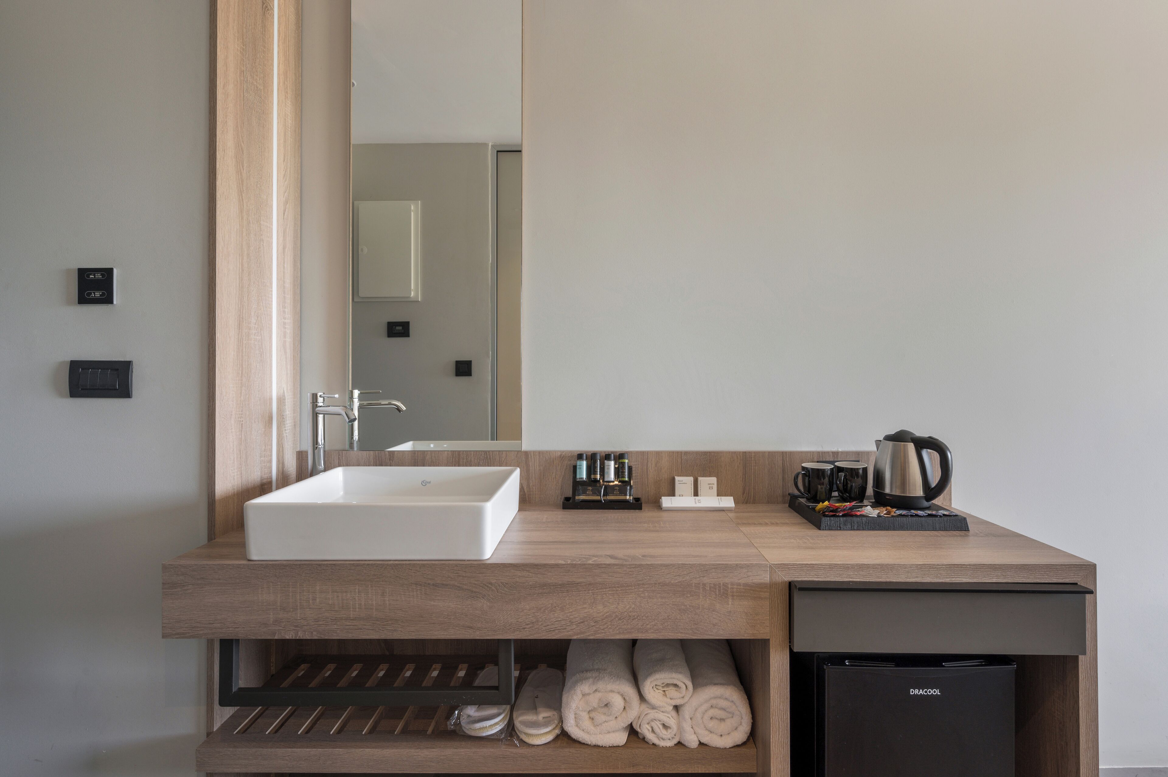A modern bathroom with a large sink, mirror, and built-in towel rack.
