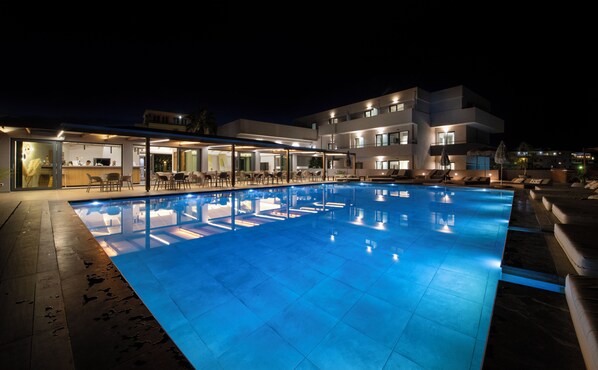 A nighttime swimming pool area with a modern building in the background.