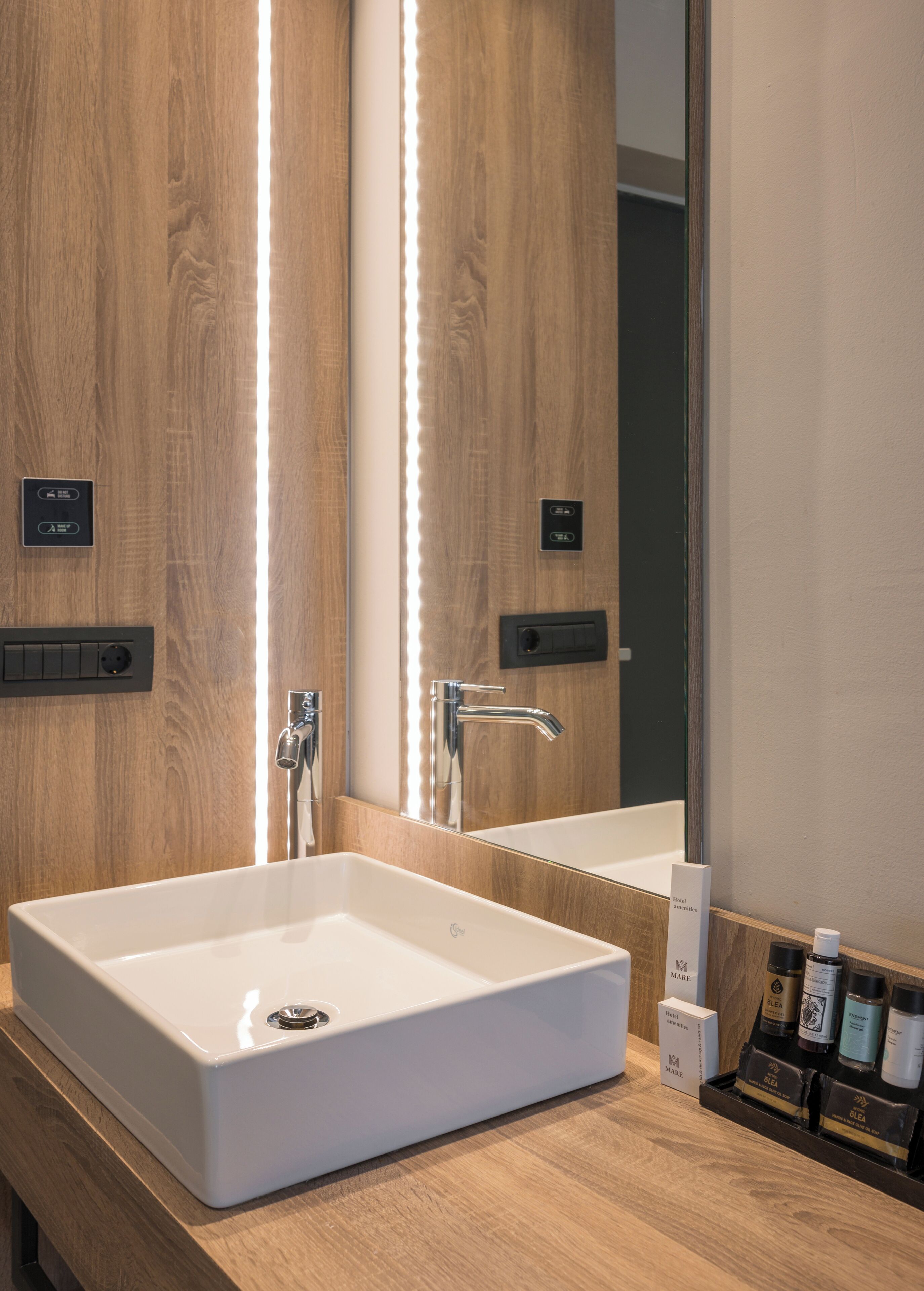A modern bathroom with a large white sink, a mirror, and wooden paneling.
