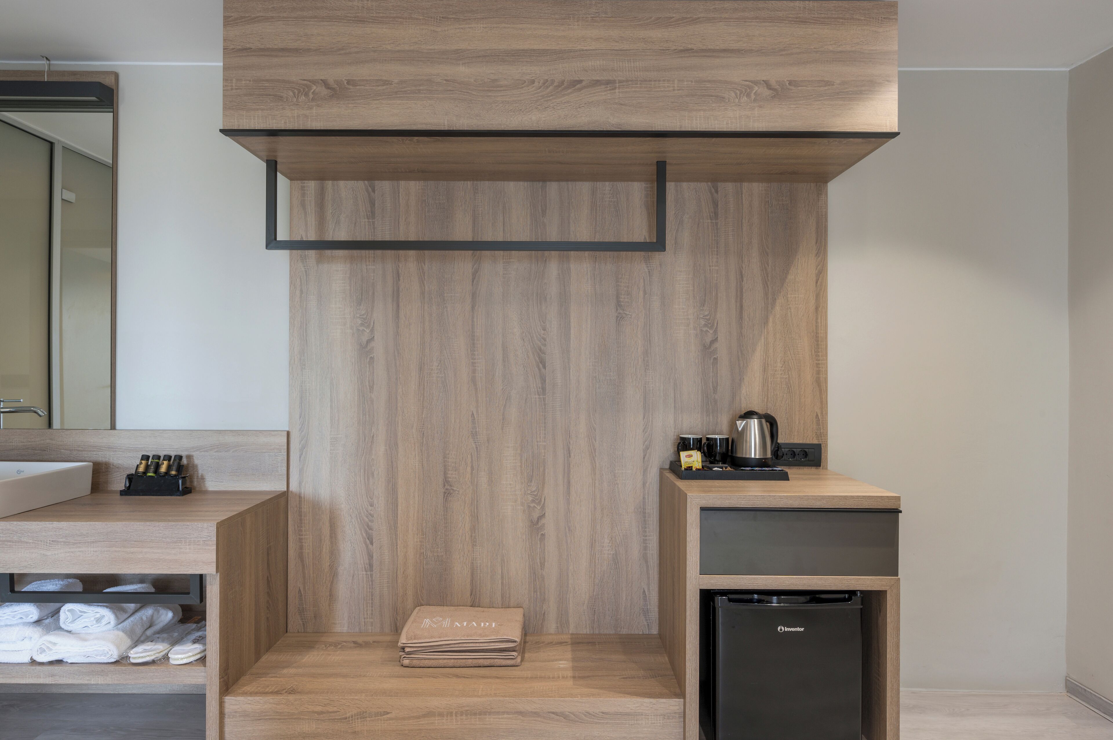 A modern bathroom with a wooden vanity, a sink, and a compact black refrigerator.