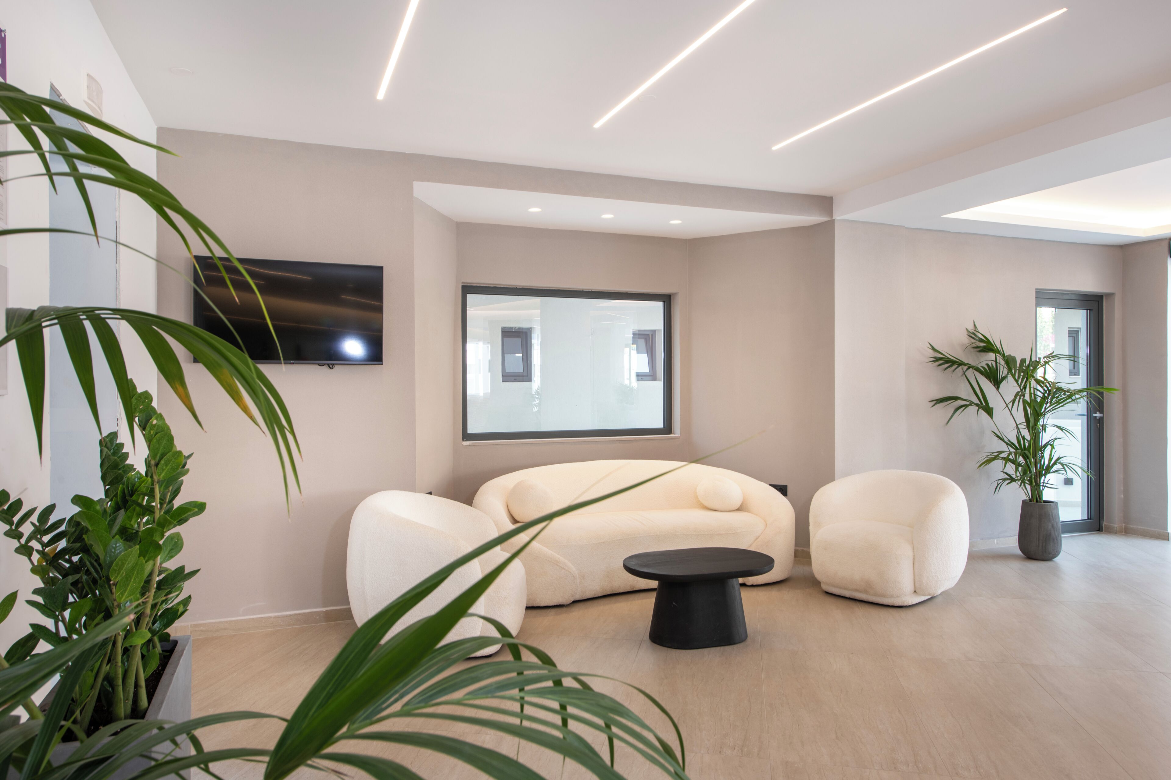 A modern living room with a large window, a flat-screen TV, and a sofa.