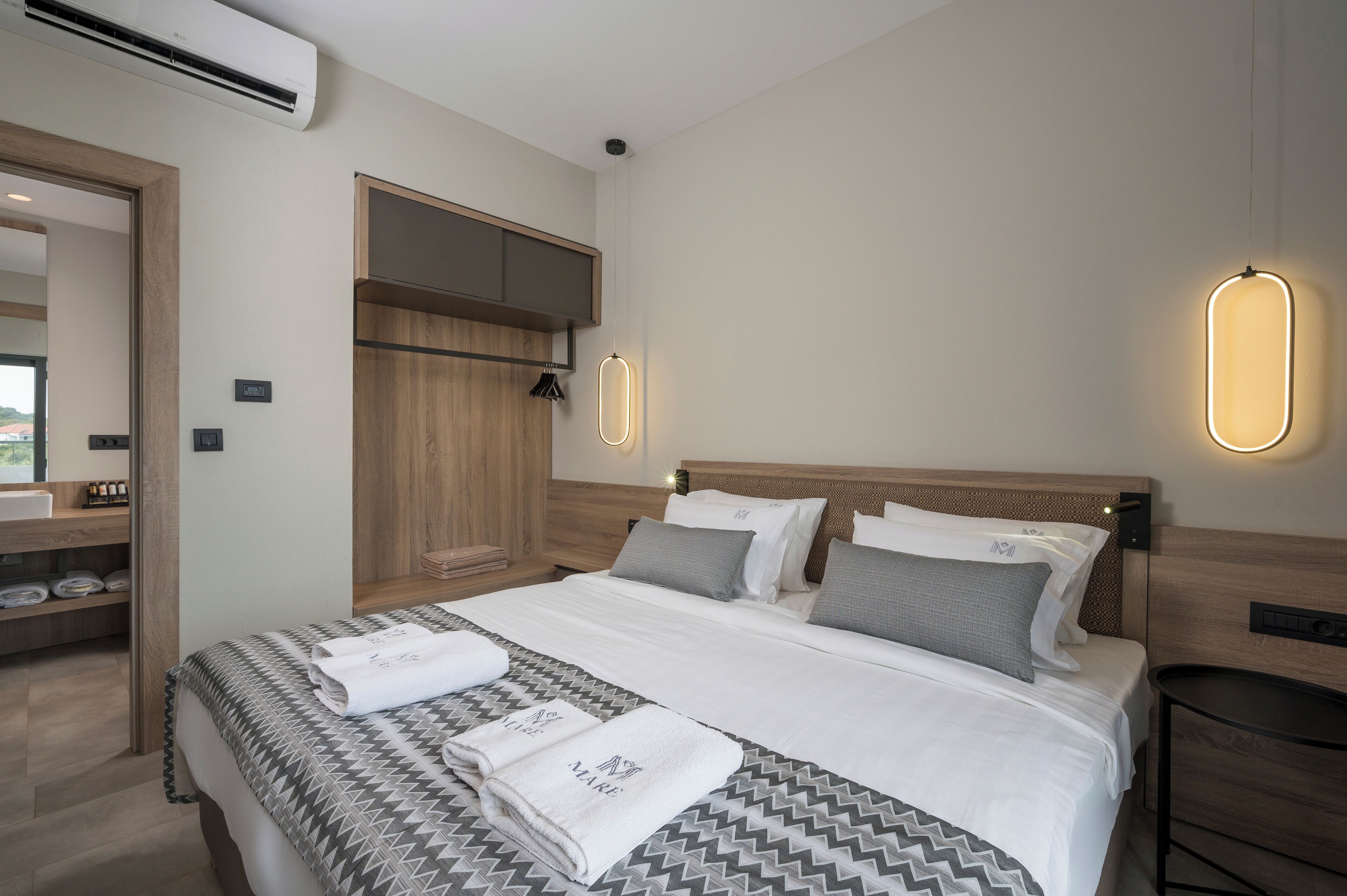 Una habitación de hotel moderna con una cama grande, cabecera de madera y mesitas de noche.