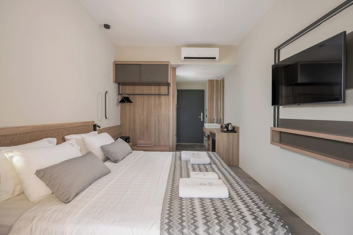 A modern hotel room with a large bed, a built-in wardrobe, a flat-screen TV, and a small bathroom.