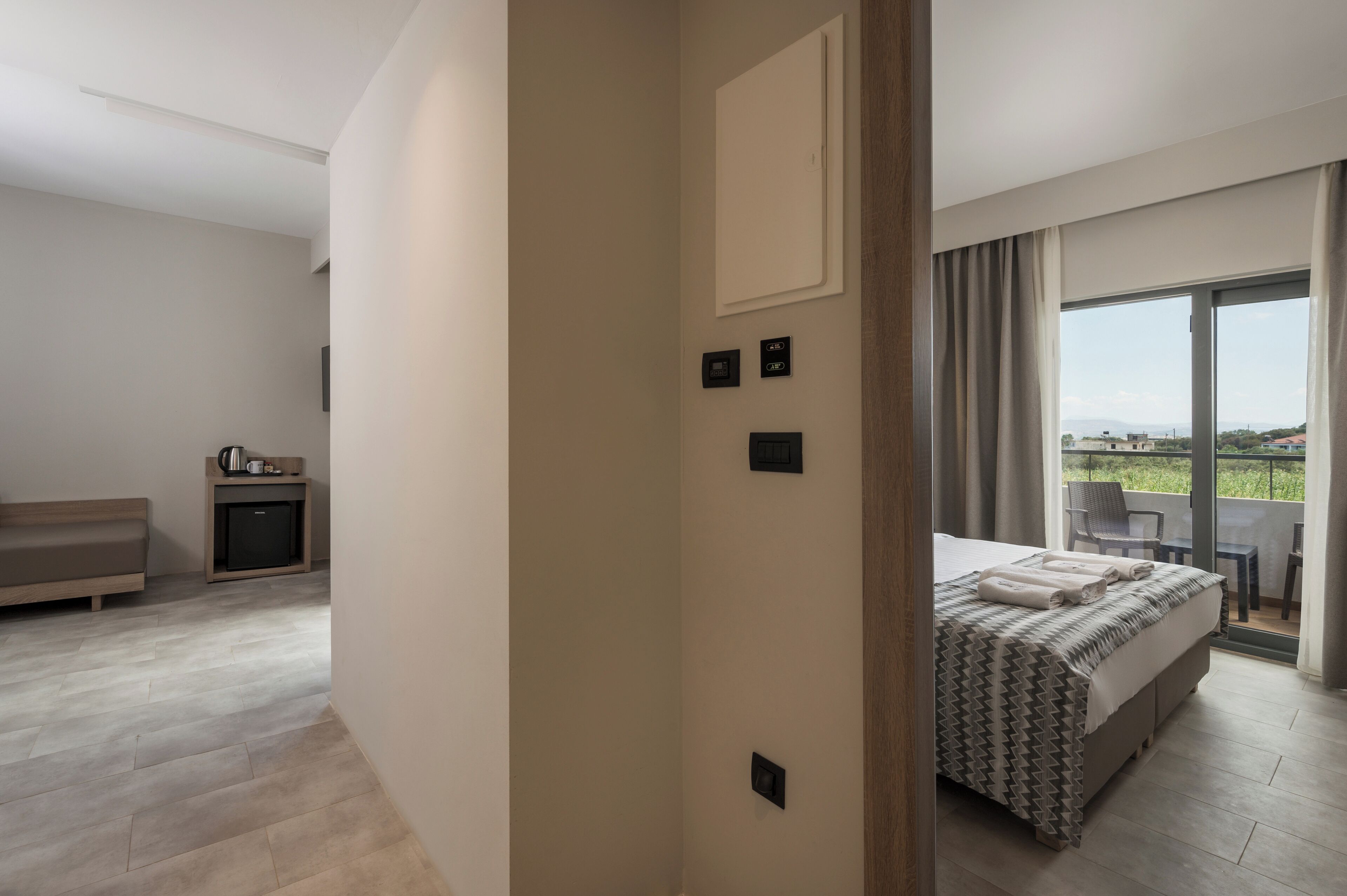 Una habitación de hotel moderna con una cama, un escritorio pequeño, un sofá y un balcón con vistas.