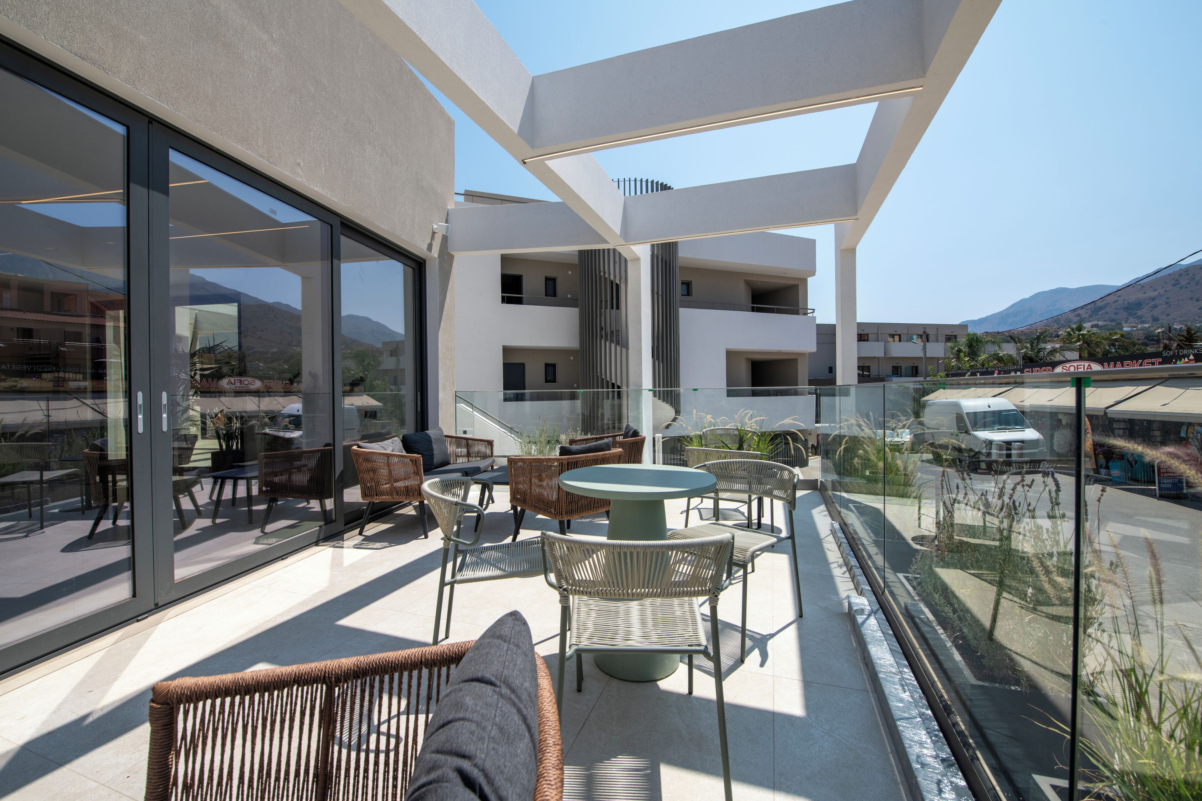 A modern outdoor patio with wicker furniture and glass doors overlooking a cityscape.