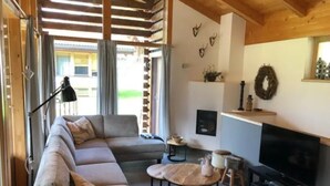 Una sala de estar moderna con un sofá seccional, una mesa de centro redonda, un televisor de pantalla plana y una chimenea.