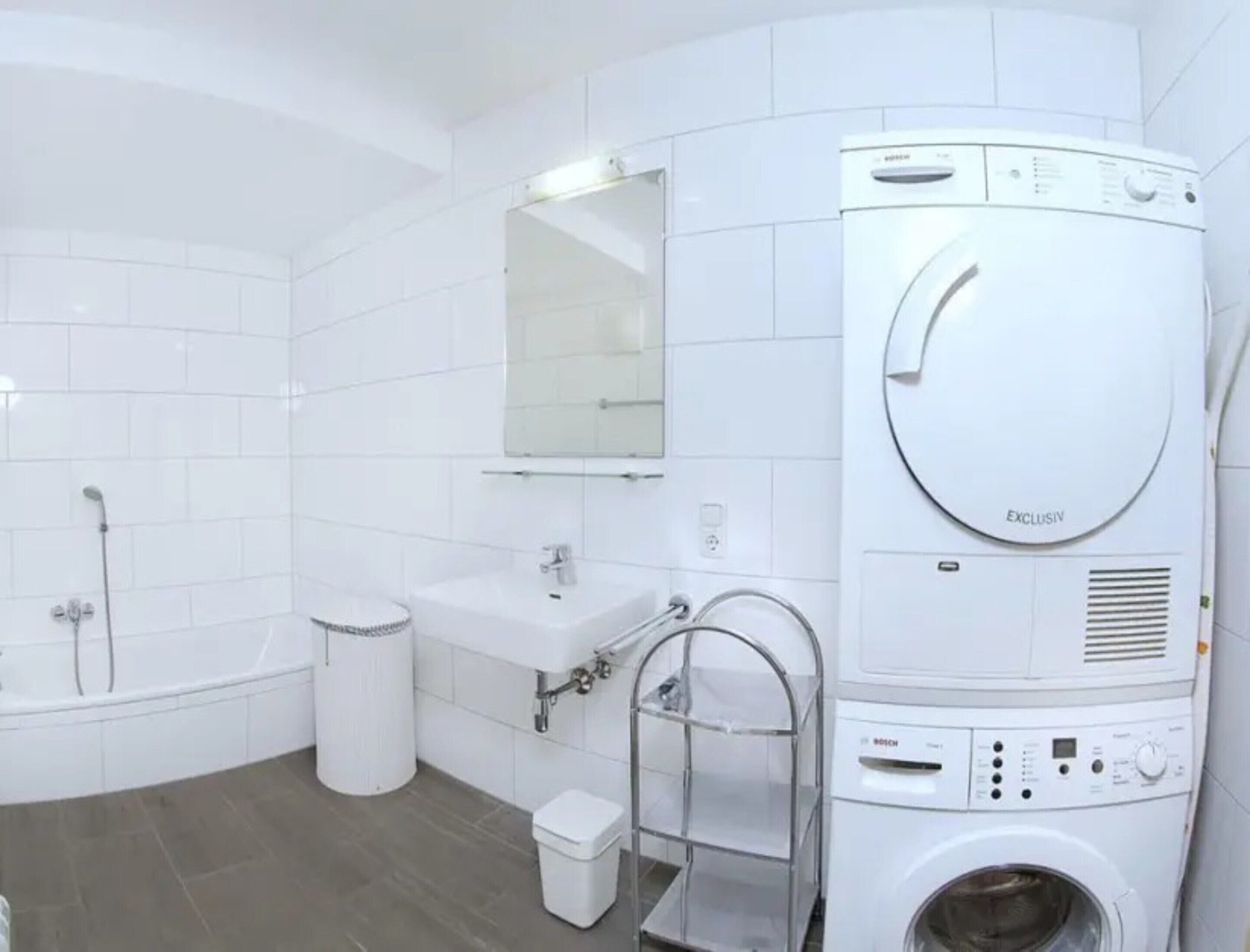 Ein modernes Badezimmer mit einer Bosch Waschmaschine, einer Badewanne, einer Toilette und einem Waschbecken.