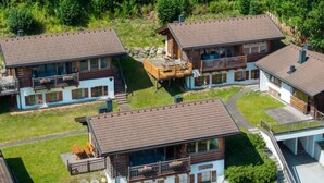 Un conjunto de edificios de estilo chalete con varios balcones, rodeado de vegetación.
