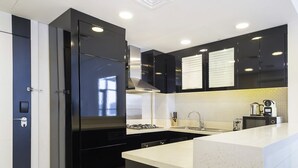 Una cocina moderna con armarios negros, encimera blanca y campana extractora de acero inoxidable.