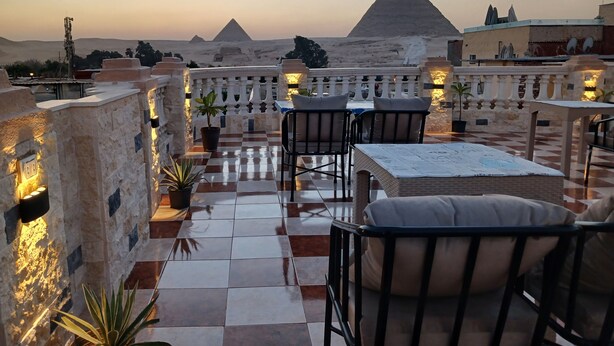 Une terrasse sur le toit avec un sol à carreaux, des sièges d’extérieur et une vue sur les pyramides.